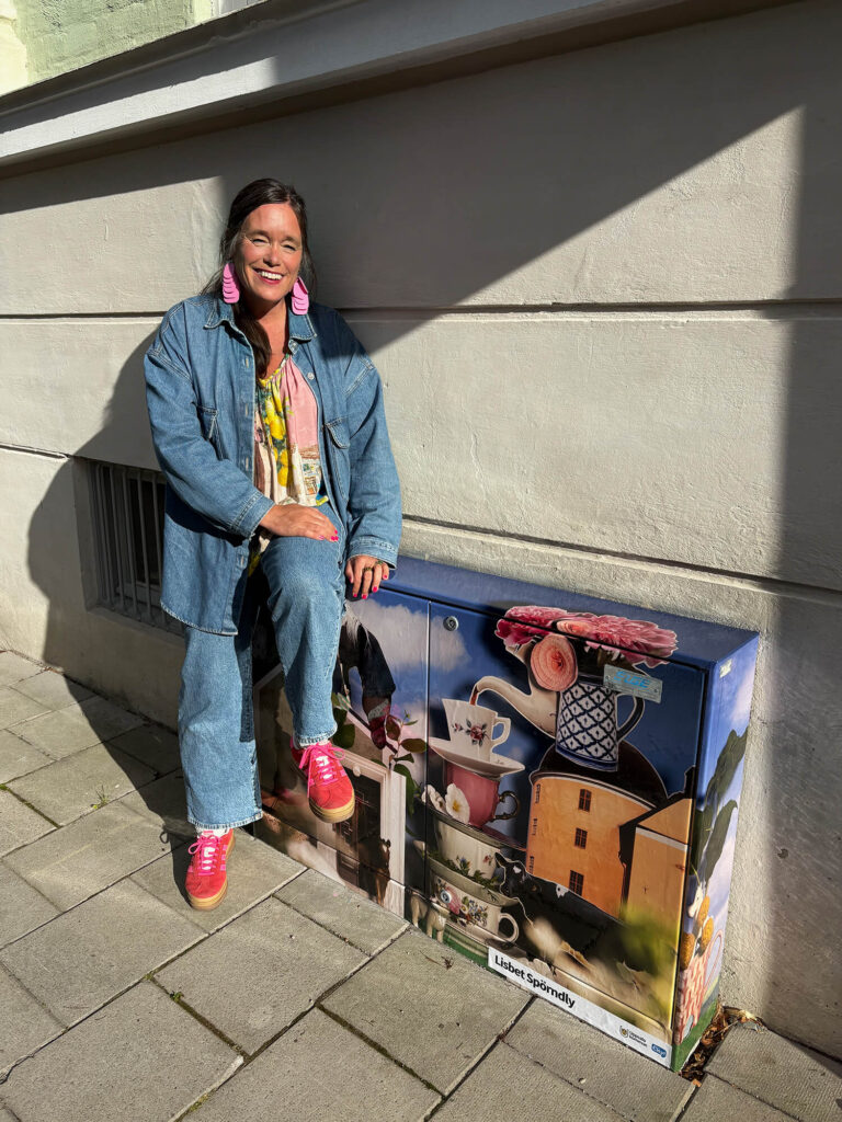 Fotografen Lisbet Spörndly sitter på det folierade elskåpet med sitt collage vivant-verk